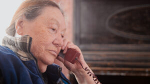 Older woman holding landline telephone, listening